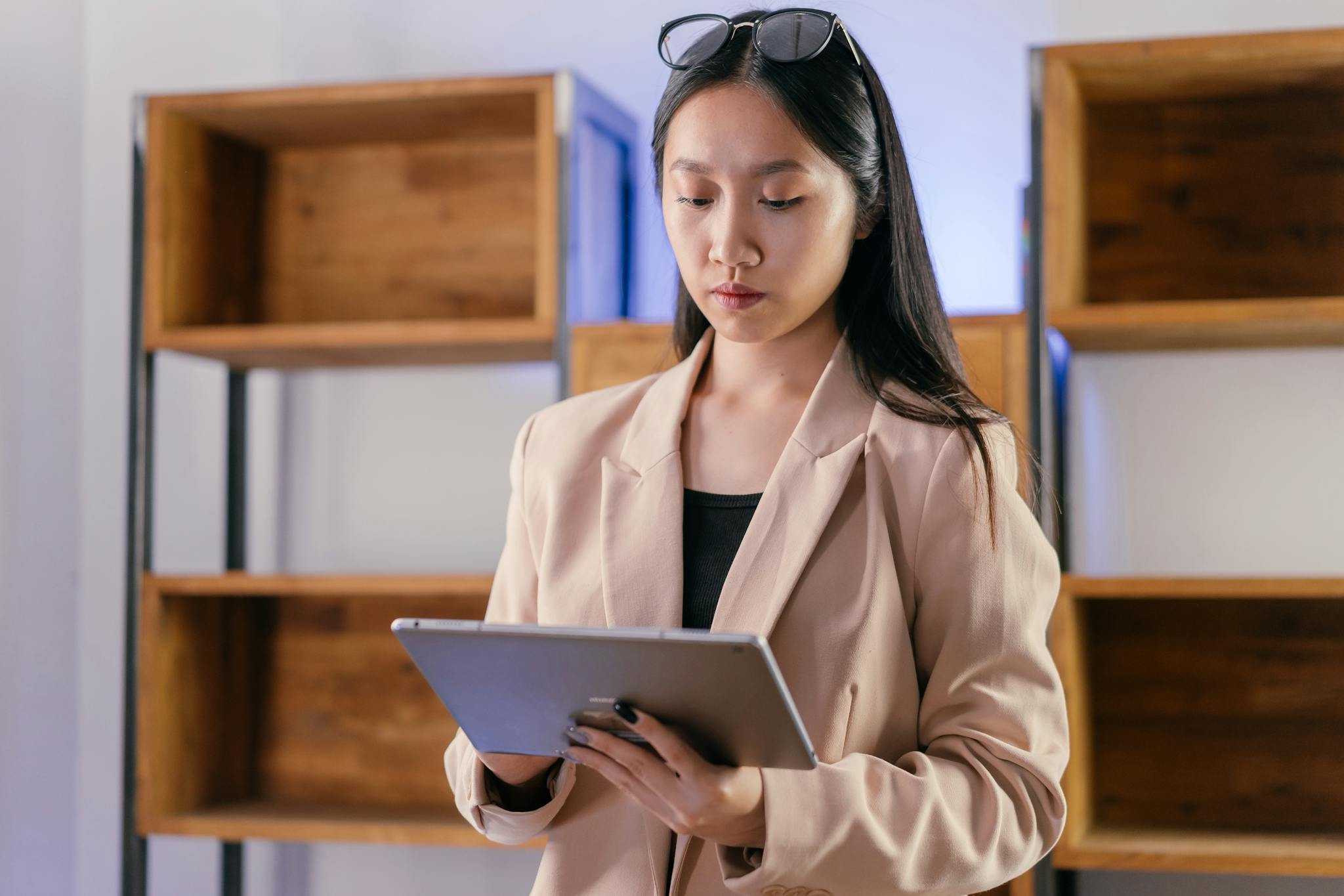 Young Asian businesswoman using a tablet in a modern office setting.
